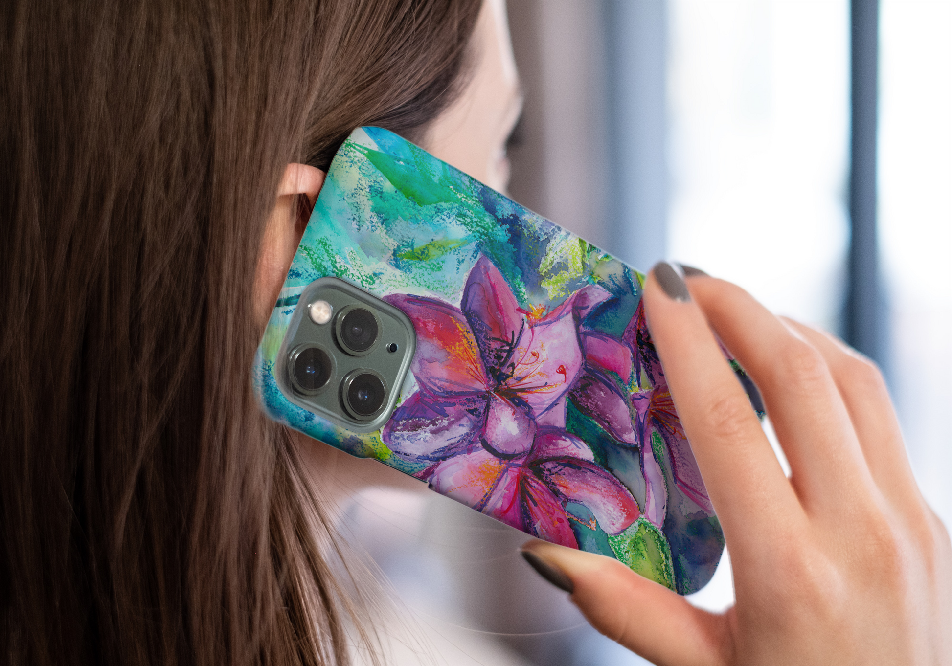 Snap on protective phone case with colourful floral art in pinks and greens shown in use, held to a woman's ear