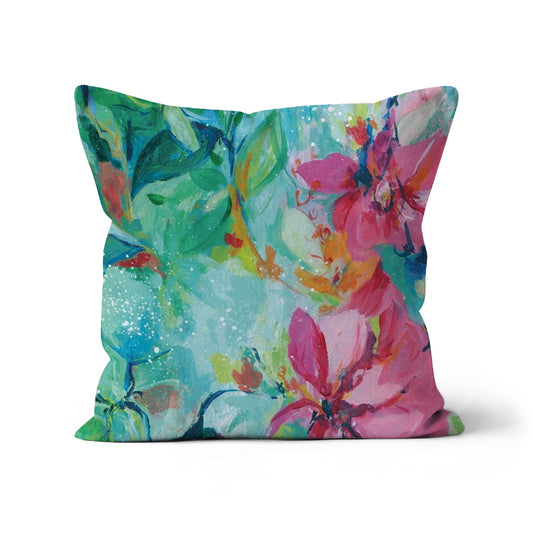 Pretty floral cushion featuring pink flowers against an aqua green lush background.