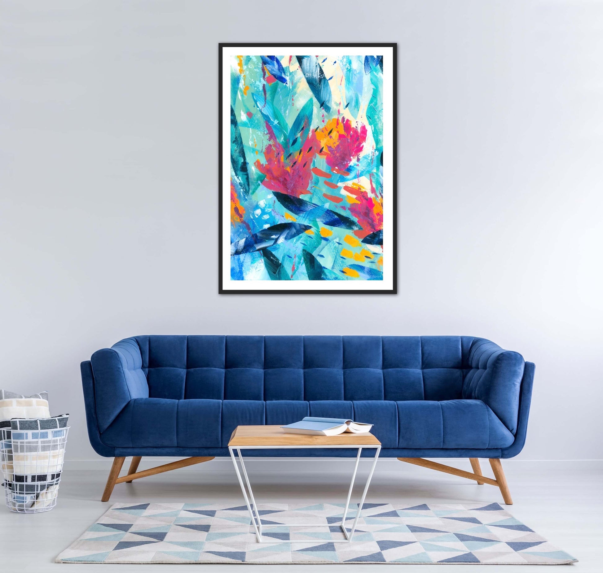 Tropical Seas colourful abstract art print displayed in a black frame on a wall in a contemporary interior decor above a blue velvet sofa.