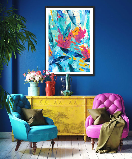 Tropical Seas colourful abstract art print displayed in a black frame on a blue wall above colourful furniture..