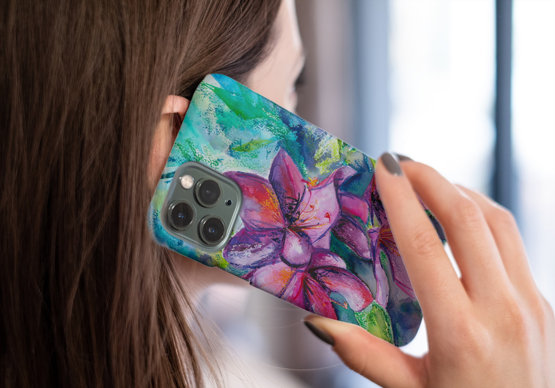 Snap on protective phone case with colourful floral art in pinks and greens shown in use, held to a woman's ear 