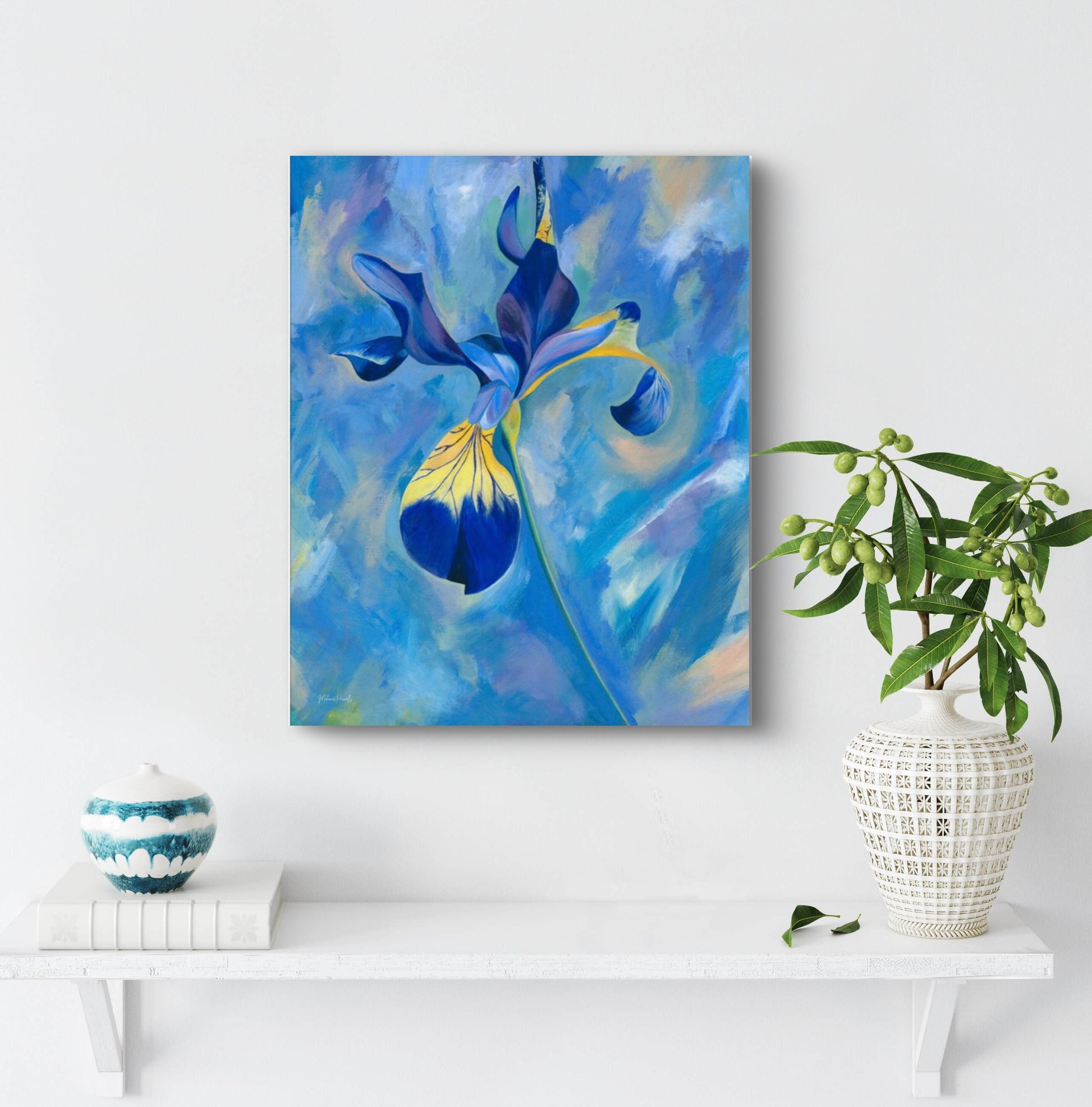 Abstract painting of a blue flower on a white wall with decorative items below.