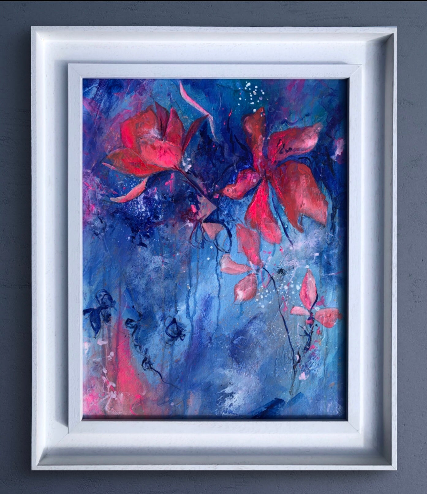 Framed painting of bright pink flowers painted on a textured blue background