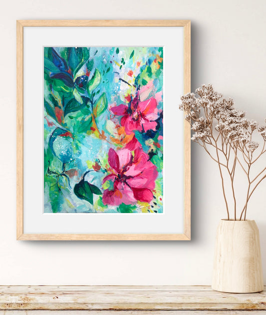 Framed colorful floral painting on a wall next to a vase with dried flowers.