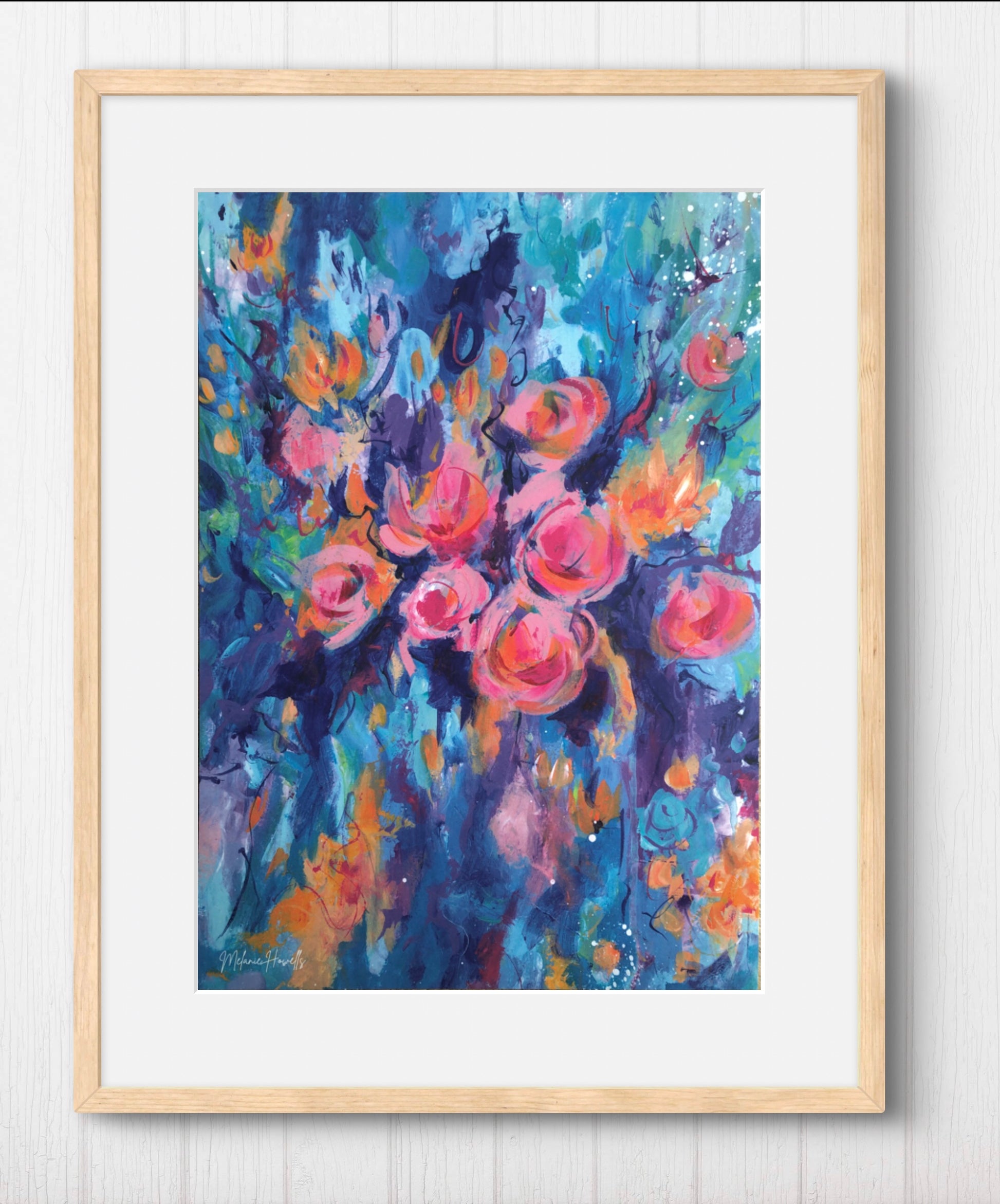 Framed floral art print featuring an expressive painting of pink and orange roses with blue and purple brushstrokes, set in a light wood frame against a white paneled wall.