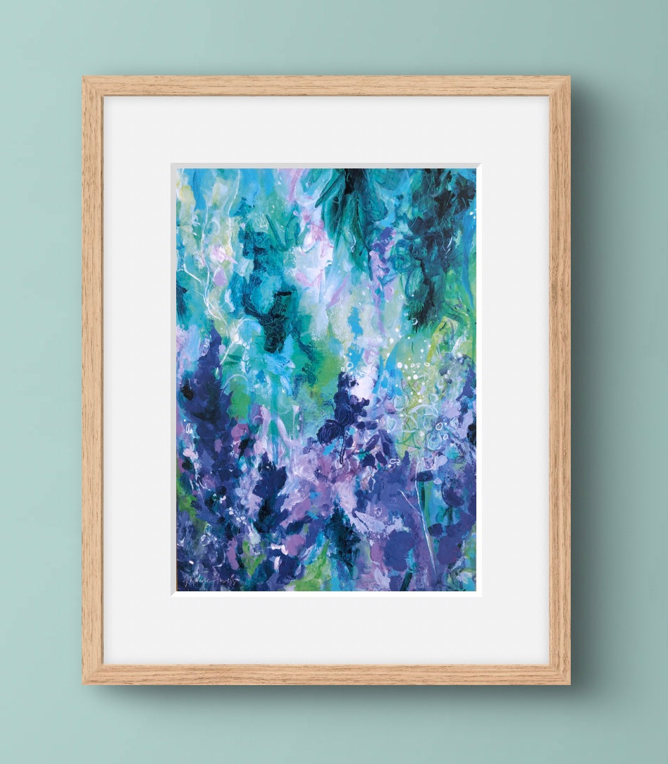 Framed abstract art print with blue and green colors on a light blue wall.
