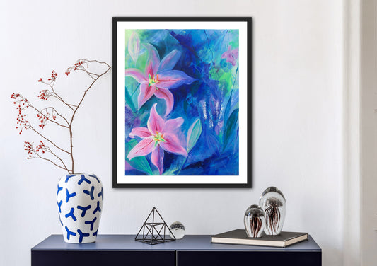 Rectangular Lilies in Bloom print in a black frame mounted on a white wall above a chest of drawers with a blue and white vase