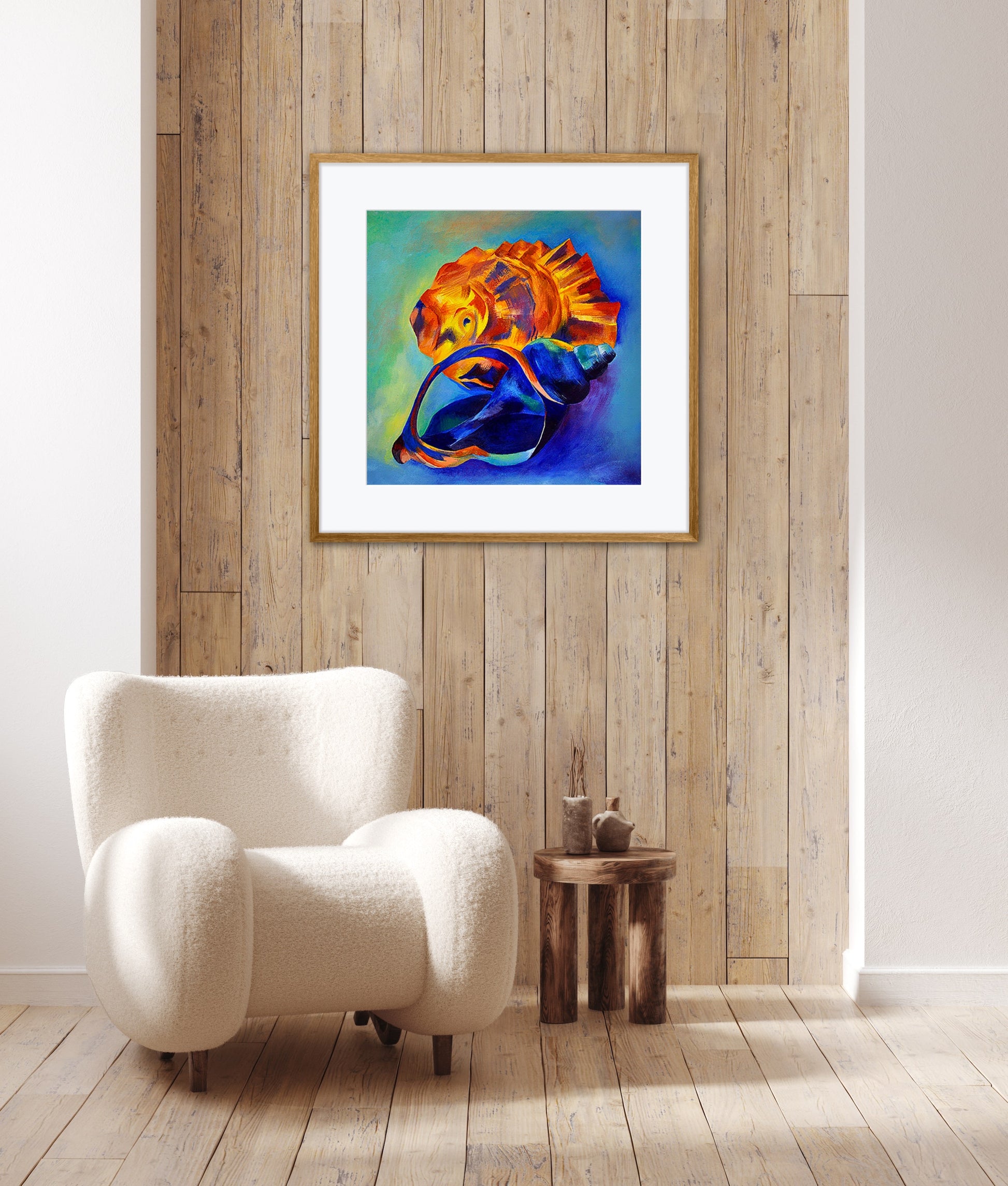 The Beachcomber colourful seashell art print displayed in a black frame on a wooden wall in a contemporary room with a white armchair