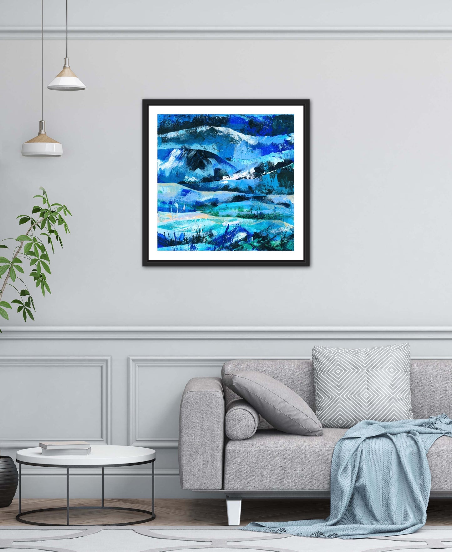 Contemporary pale grey living room with a pale grey sofa and a blue abstract landscape art print displayed in a black frame on the wall behind the sofa