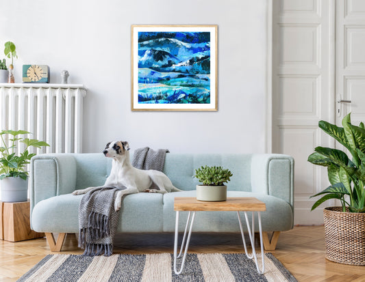 Living room with pale aqua sofa with dog on and blue abstract landscape painting framed on the wall behind the sofa